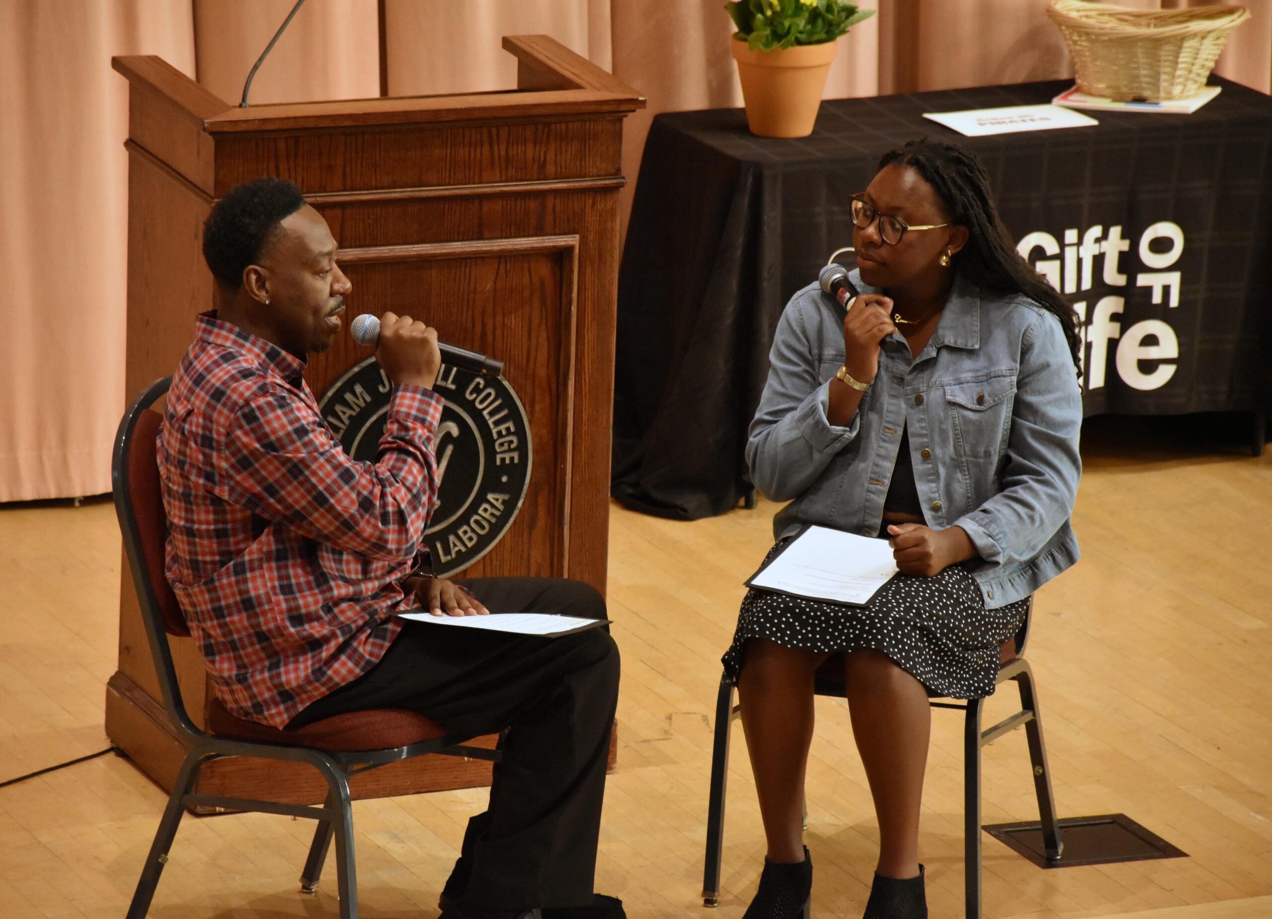 Picture of an African American Man and Women on a stage talking